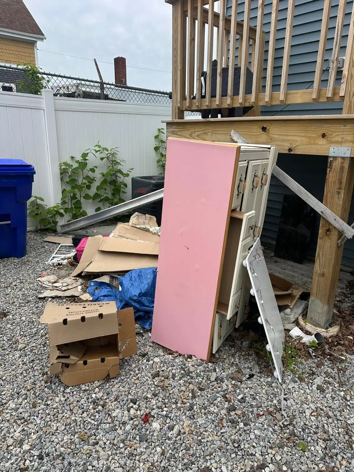Boxes, boards and a tarp piled under a back deck before junk removal