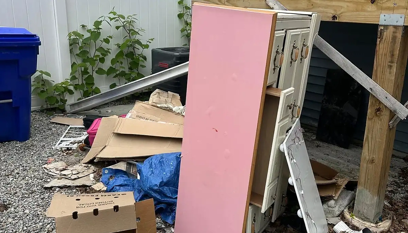 Boxes, boards and a tarp piled under a back deck before junk removal