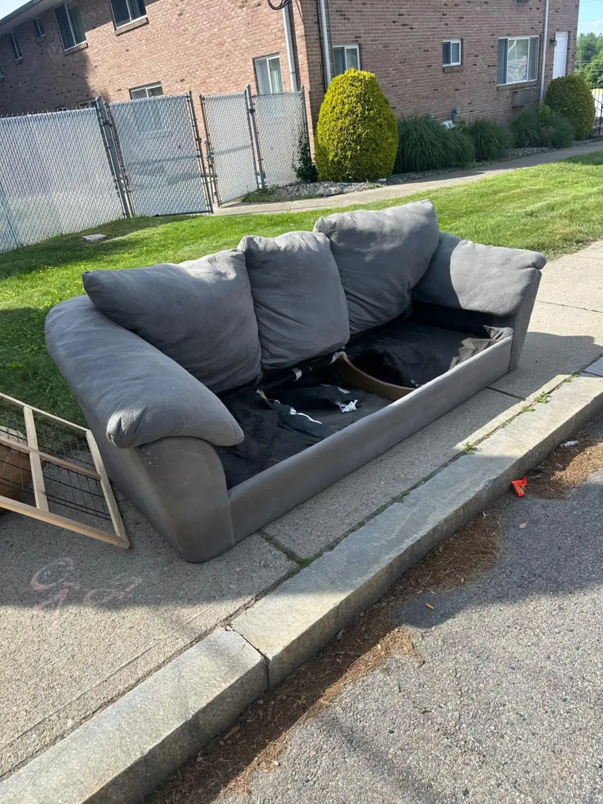 Grey couch left at the curb before pickup in Rhode Island