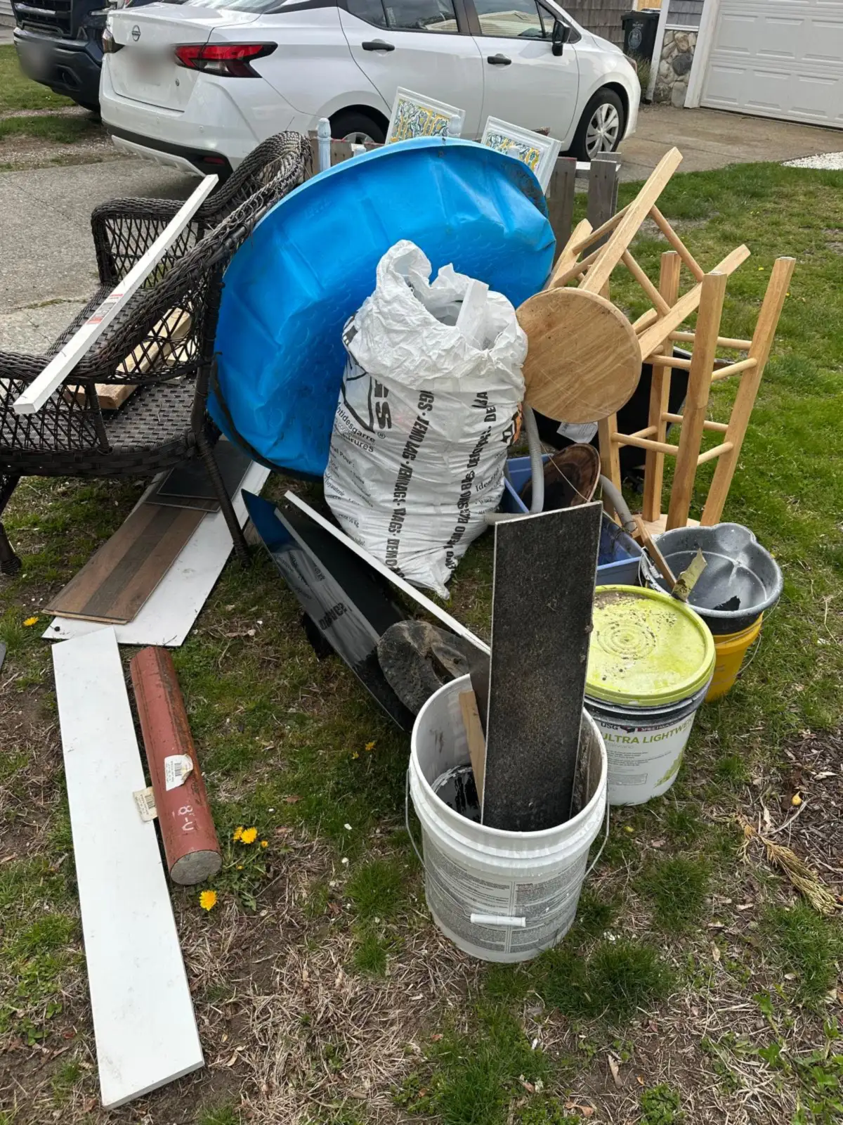 Kiddie pool, buckets and stools piled on a front lawn before removal