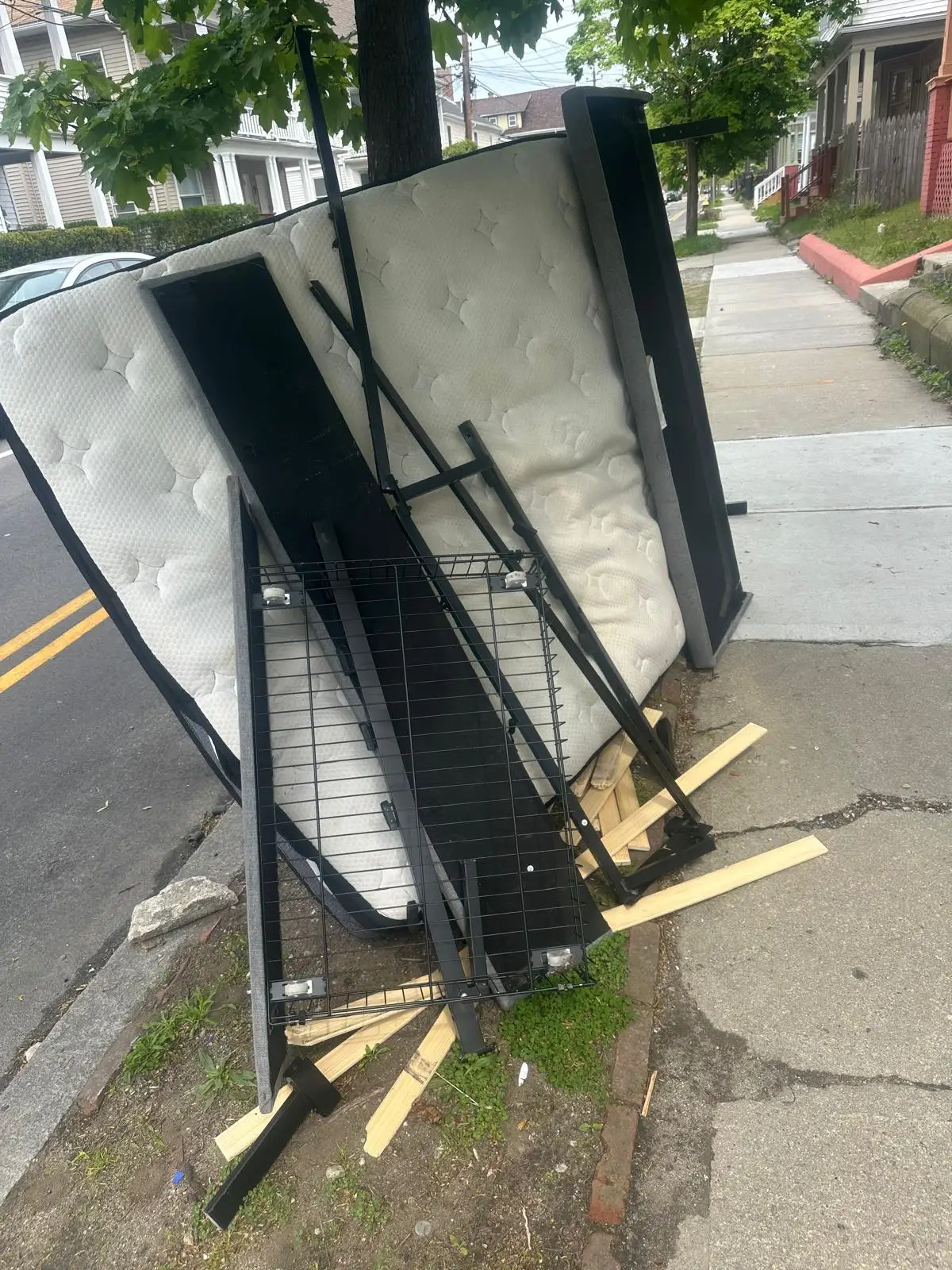 Mattress and metal bed frame left at the curb before pickup