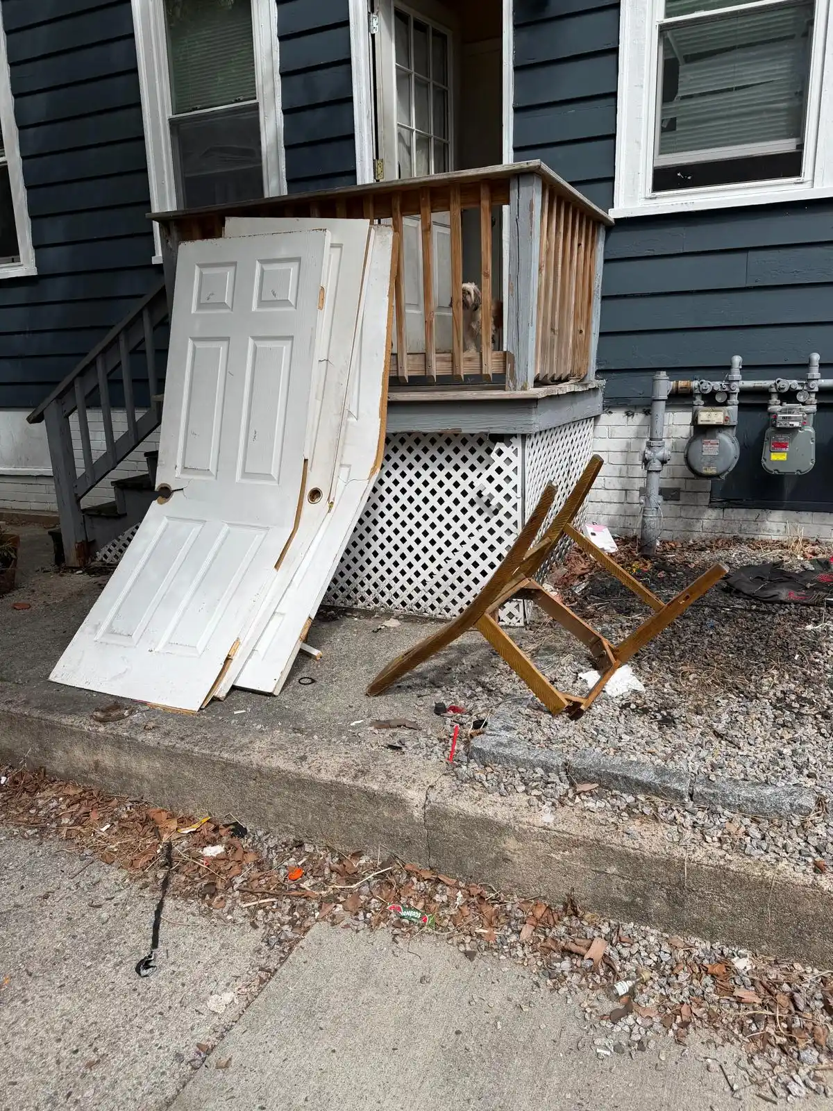 Old doors and a broken chair leaning on a back porch before removal