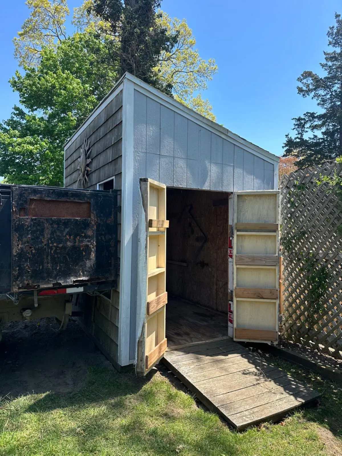 Grey shed beside the trailer before demolition and removal