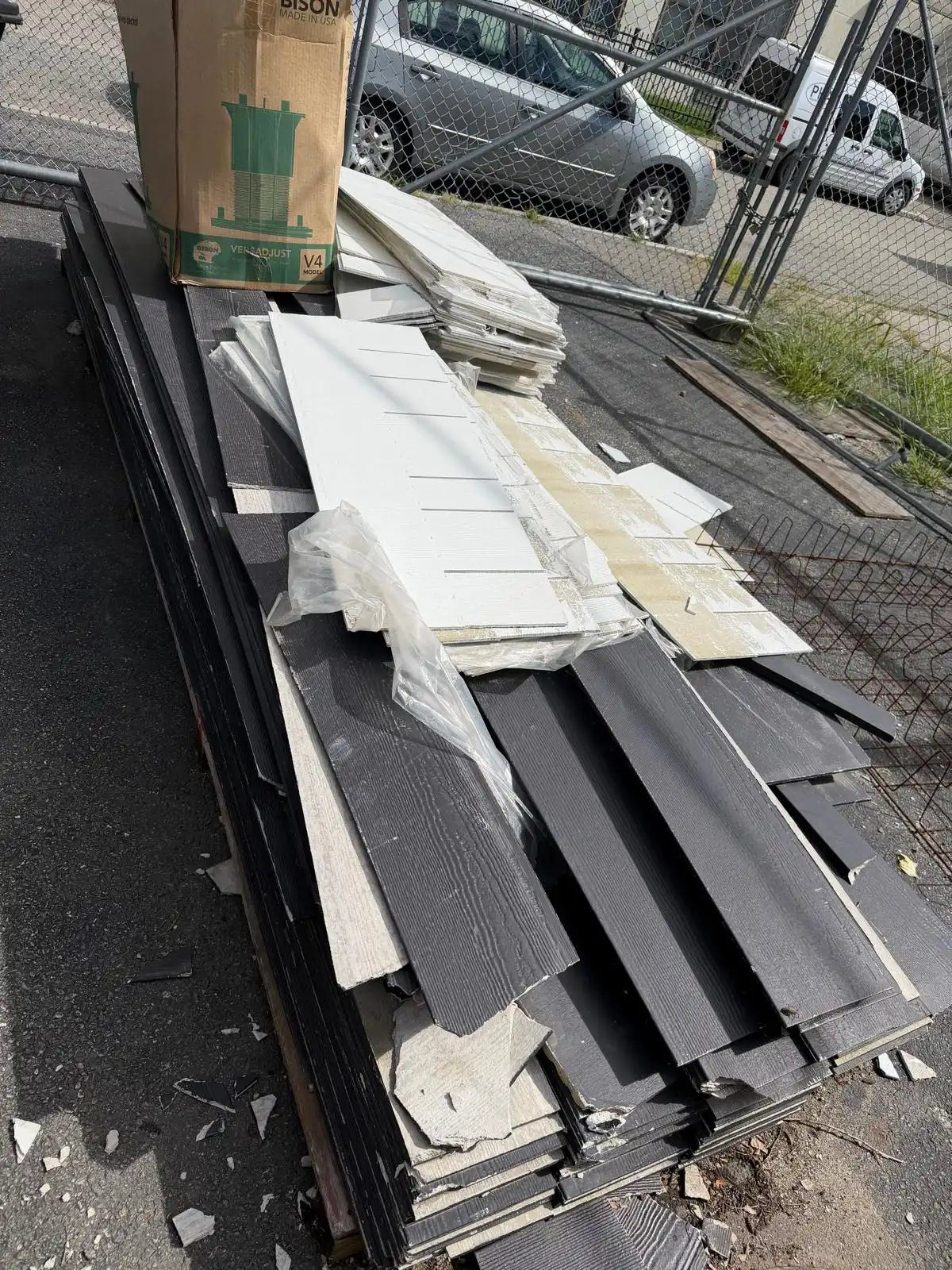 Stack of old siding and building debris in a lot before removal in Rhode Island